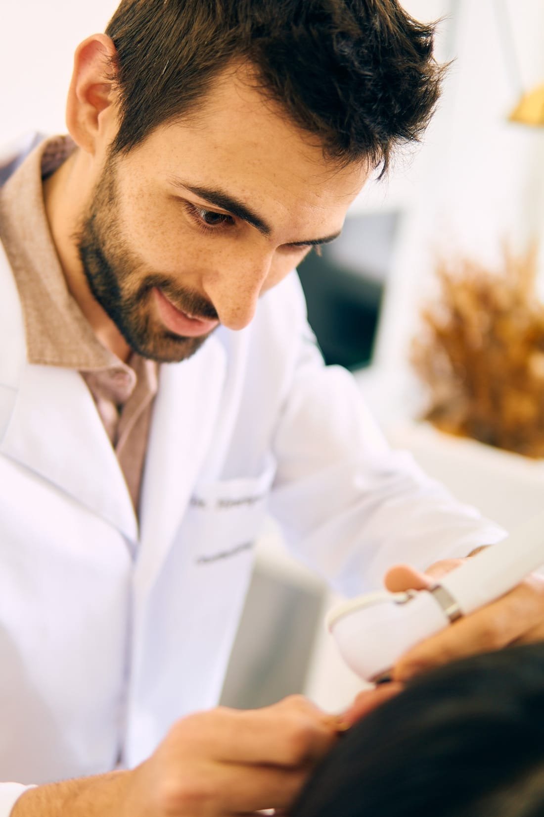 Dr. Henrique Alessi sorrindo enquanto examina um paciente
